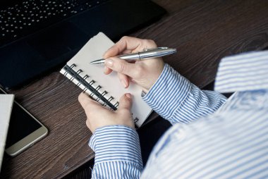Close-up of man writing on a notebook with pen