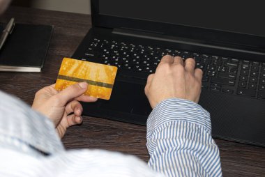 Kadın ellerinin kredi kartı tutarak ve bilgisayar kullanarak arkadan bakmasını. Çalışma alanı. Altın kredi kartı.