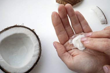 Kadın ellerine doğal krem sürüyor. Kadın elleri üst görüntüye yakın çekim. Beyaz arka planda hindistan cevizi içeren organik kozmetik ürünler.. 