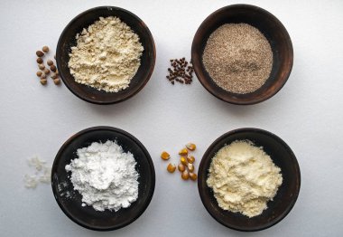 Çeşitli glütensiz un - nohut, pirinç, karabuğday, mısır, pirinç. Kil tabakta un. Un ve mısır gevreği yakında.. 