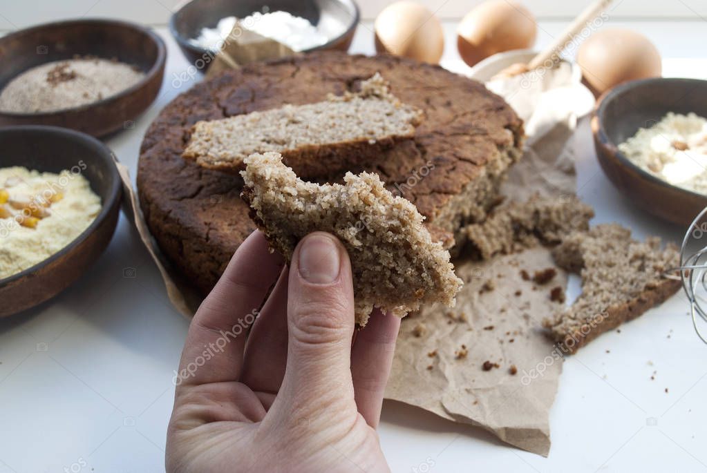 Various gluten-free flour. Round gluten free homemade bread. Buckwheat, chickpea, rice, corn flour, eggs and honey. healthy eating concept, flat lay. A piece of bread in a female hand.