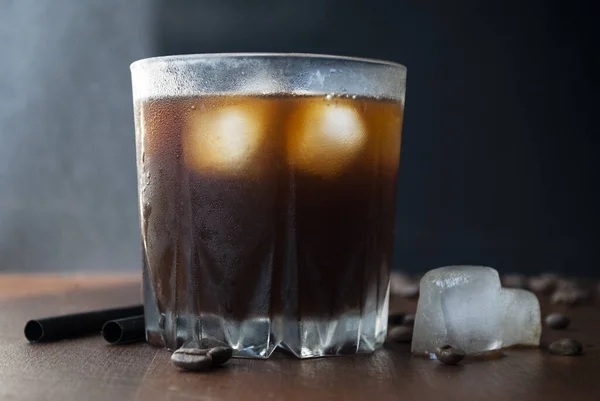 iced coffee, glasses of cold cold coffee. Dark chocolate and coffee beans. Side view, dark background.