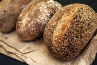 Glütensiz yemek. Karabuğday çörekleri. Tahtada üç rulo. Karabuğday glütensiz ekmek. Siyah arkaplan.