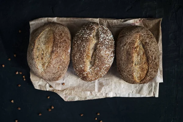 Gluten free food. Buckwheat buns. Three rolls on a wooden board. Buckwheat gluten-free bread. Black background.