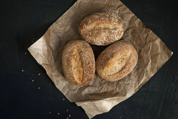 Gluten free food. Buckwheat buns. Three rolls on a wooden board. Buckwheat gluten-free bread. Black background.