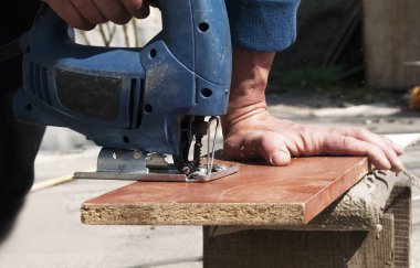 Çalışan ve demir testeresiyle odun kesen adam