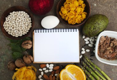 Yüksek miktarda B9 vitamini içeren yiyecekler. Sağlıklı yiyecekler, folik asit kaynakları. Boş bir defter. Kopyalama alanı olan üst görünüm. Hamile ve emziren anneler için diyet gereklidir. Kopyalama alanı olan üst görünüm.