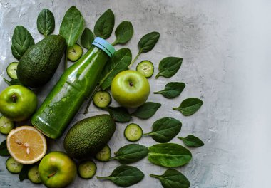 Yeşil smoothie, kompozisyon: ıspanak, salatalık, elma, limon, avokado, doru. Gri arka plan detoks içeceğine ve bileşenlerine güzelce yerleştirilmiş..