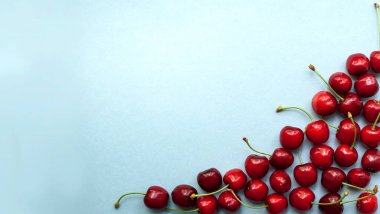 Kompozisyon, köşedeki çerçeve, tatlı kirazdan oluşmuş. Mavi arkaplan ve metin için yer. Üst manzara, düz uzanma.