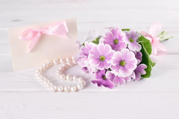 Bouquet de primevères violettes avec carte de voeux en papier — Photo