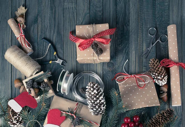 Fundo de Natal. Presentes embalados e pergaminhos, ramos de abeto e ferramentas em mesa de madeira gasto . — Fotografia de Stock