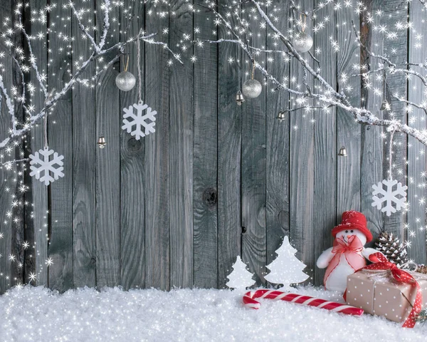 Рождественский интерьер с декоративными ветками, подарками и конфетами на фоне деревянных досок . Стоковая Картинка