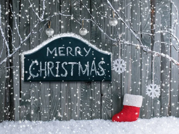 Рождественский интерьер с декоративными ветками, ботинок Санты, вывеска с поздравлениями и снегопадом — стоковое фото