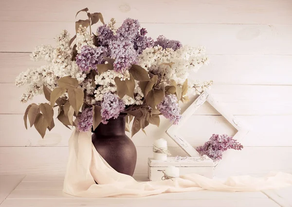 Bouquet lilla in brocca di argilla con cornice e candele — Foto Stock