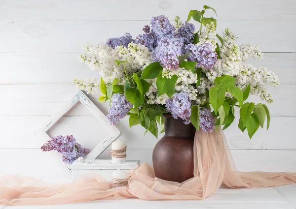 Buquê de lilás em jarro de barro com moldura de foto e velas — Fotografia de Stock