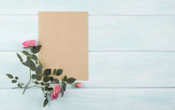 Fundo de madeira com rosas e papel ecológico vazio — Fotografia de Stock