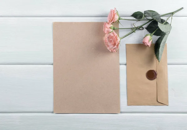 Fundo de madeira com rosas, envelope e papel eco — Fotografia de Stock