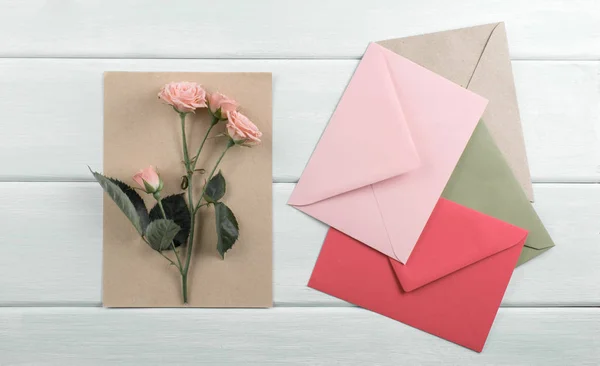 Fundo de madeira com rosas, envelope e papel eco — Fotografia de Stock