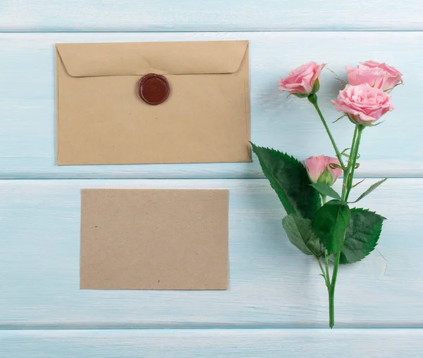 Fundo de madeira com rosas, envelope e papel eco — Fotografia de Stock