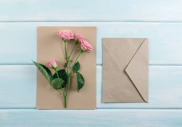 Fundo de madeira com rosas, envelope e papel eco — Fotografia de Stock