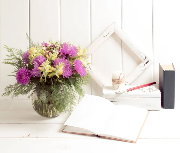 Квітковий букет у вазі з відкритим щоденником, книгою та рамкою — стокове фото