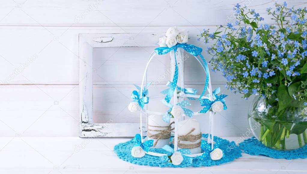 Forget-me-not flowers with birdcage and photo frame and candles 