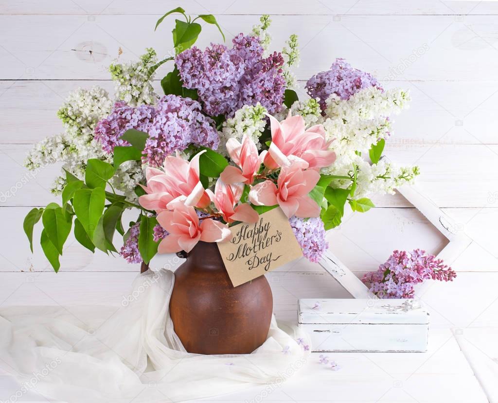 Lilac bouquet and magnolia in jug with congratulatory card