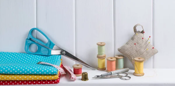 Set di strumenti per il cucito e tessuto sdraiato sul ripiano in legno — Foto Stock
