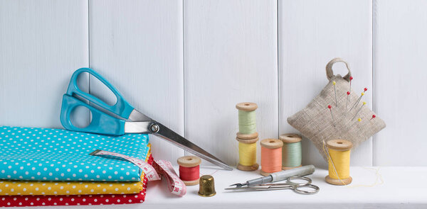 Set of tools for sewing and fabric lying on the wooden shelf