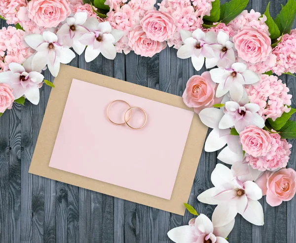 Rosas, magnólias, hortensia e anéis de noiva com cartão de papel — Fotografia de Stock