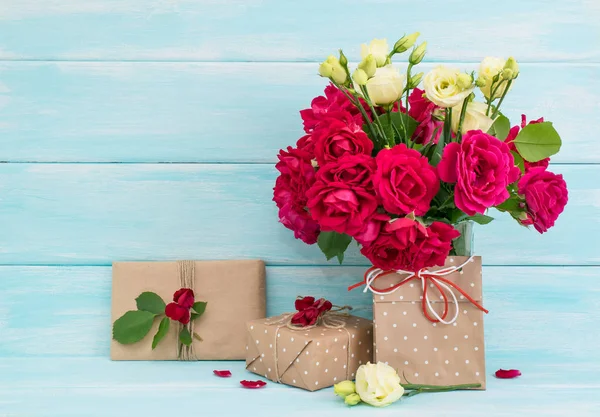 Bouquet di rose e regali su sfondo di legno — Foto Stock