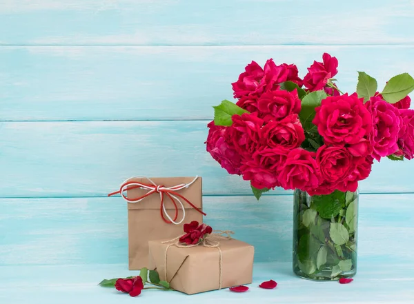 Bouquet di rose e regali su sfondo di legno — Foto Stock