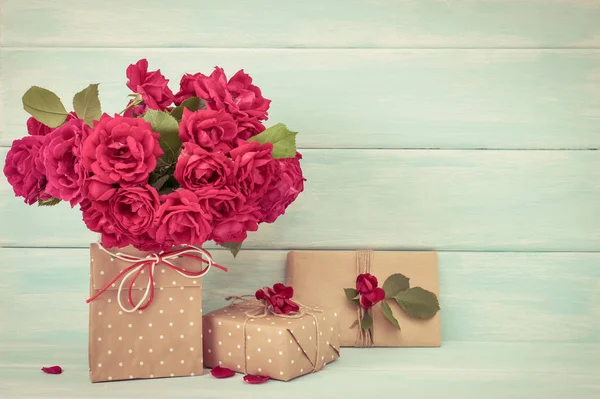 Bouquet di rose e regali su sfondo di legno — Foto Stock