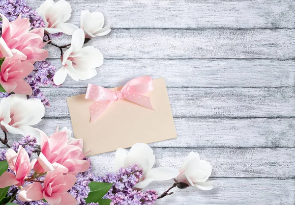 Magnólia, flores lilás e cartão em tábua rasgada — Fotografia de Stock