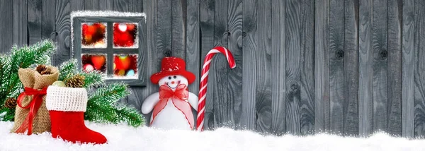 Bota Santa con regalos y muñeco de nieve sobre fondo de pared de madera — Foto de Stock