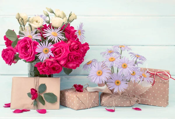 Roses and daisy bouquet with gifts on wooden background — Stock Photo, Image