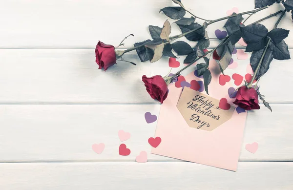 Rose rosse con cuori di carta e biglietto di auguri — Foto Stock