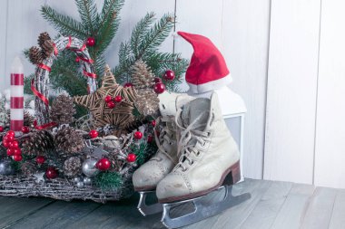 Hasır şenlik sepeti, buz pateni için patenler, fener, mum, Noel Baba şapkası, köknar ağacı eski püskü masa.