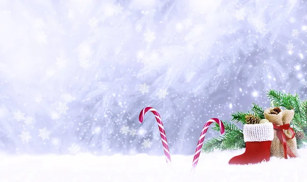 Tarjeta fabulosa de Navidad con bota de Santa Claus, bolsa de regalo, piruletas de bastones de caramelo en el fondo de nieve de invierno con nevadas y copos de nieve —  Fotos de Stock