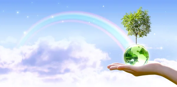 Card for World Earth Day. Planting trees, Ozone Day concept. Saving environment, save and protect green planet and ecology. Earth globe and growing tree in hand on stars sky and rainbow background.