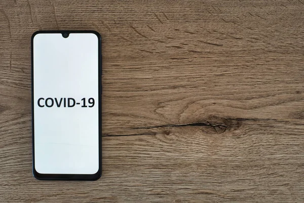 Masanın üzerinde covid-19 gösteren cep telefonu.