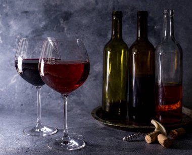 Kırmızı şarap. Şişe ve bir bardak kırmızı şarap. Eski tarz. Siyah arka planda kırmızı şarap. Metnin için boşluk ile tasarım yap.