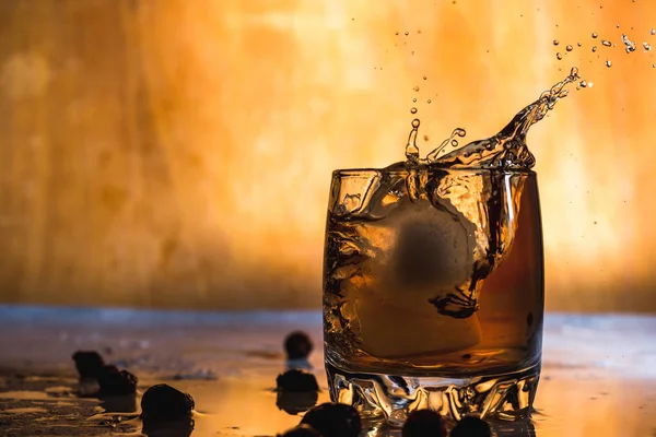 Hideg Jég Fröccsenése Egy Üveg Whiskey Ben Könnyű Háttérrel Elszigetelve — Stock Fotó