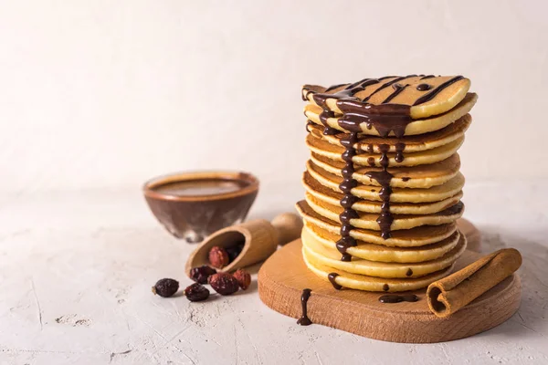 Çikolata reçelli taze krepler, tarçın çubukları ve gri bir zemin üzerinde şekerlemeler.