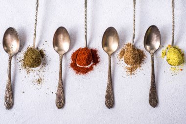 Çeşitli baharatlar. Zerdeçal biberli zencefilli tarçınlı bitki. Masanın üzerinde kırmızı biber aromalı karanfil tohumları var. Yukarıdan bak. Beyaz arkaplanda Hint baharatları