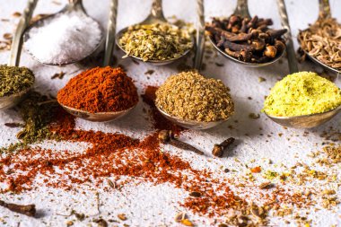 Çeşitli baharatlar. Zerdeçal biberli zencefilli tarçınlı bitki. Masanın üzerinde kırmızı biber aromalı karanfil tohumları var. Yukarıdan bak. Koyu mavi arka planda Hint baharatları