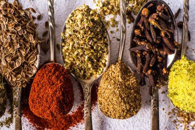 Çeşitli baharatlar. Zerdeçal biberli zencefilli tarçınlı bitki. Masanın üzerinde kırmızı biber aromalı karanfil tohumları var. Yukarıdan bak. Koyu mavi arka planda Hint baharatları