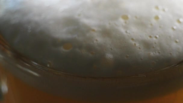 Cerveja gelada é derramada e espuma sai do copo de cerveja na mesa — Vídeo de Stock