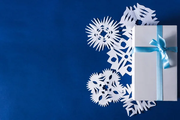 Beyaz kağıttan kesilmiş çeşitli Noel temalı kar tanelerinin arka planı, modaya uygun mavi arka plan 2020