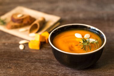 Kırsal ahşap bir masada sağlıklı kremalı balkabağı çorbası. Sonbahar balkabağı kremalı çorba biberiye ve kızarmış ekmek. Boşluğu kopyala